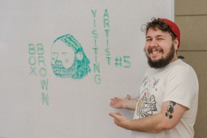 Box Brown in front of his name board, drawn by Luke Howard.